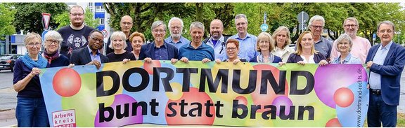 Vertreter*innen der Mitgliedsverbände im Arbeitskreis gegen Rechtsextremismus hinter dem Banner "Dortmund bunt statt braun"